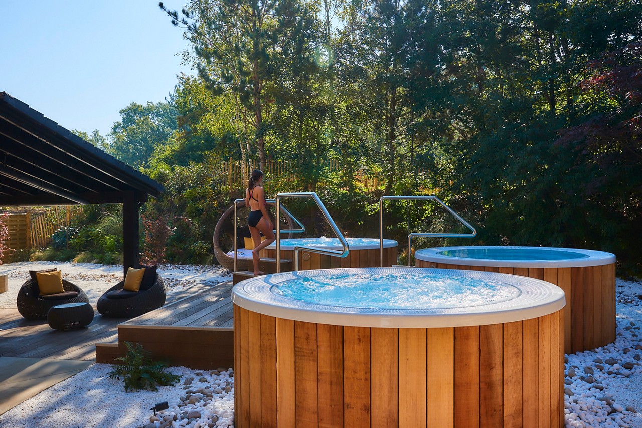 Woman stepping into a bubbling outdoor hot tub.